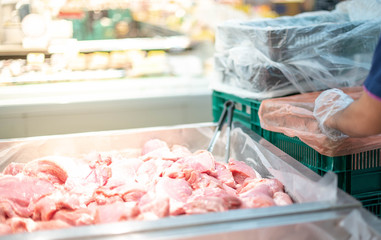 The supermarket employee preparing the Fresh pork meat slice on display tray for consumers select in a supermarket.