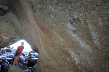 Australian tourist girl looking at ancient Aboriginal Australian indigenous rock painting