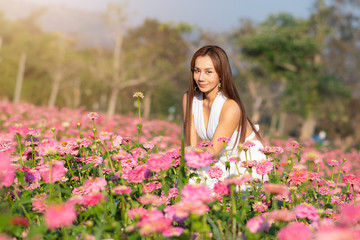 Obraz na płótnie Canvas happy young woman enjoying summer in zinnia field. Beautiful woman relaxing in pink flower garden.