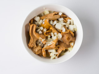 Marinated mushrooms Redheads in a white bowl with onions and vegetable oil. Top view