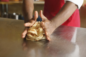 Man loosening the texture of roti canai to make them tastier