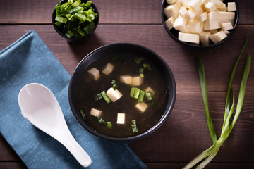 Japanese hot miso soup in a black bowl on the wooden table. Horizontal view from above.