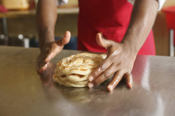 Man loosening the texture of roti canai to make them tastier