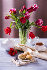 Tasty apple muffins with a beautiful bouquet of red tulips on a wooden background.