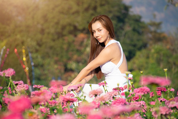 happy young woman enjoying summer in zinnia field. Beautiful woman relaxing in pink flower garden.