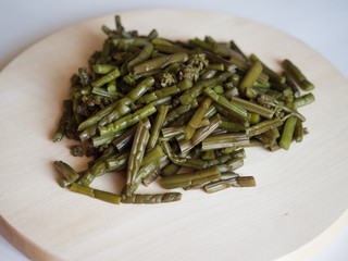 Young pickled fern on the round wooden board. Sliced for further cooking