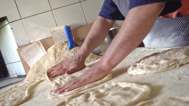 Vertigo shot of baker man rolling out fresh dough to make Ramadan bread
