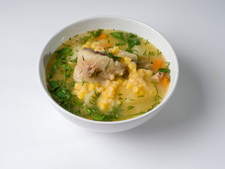 Pea soup with meat in a white bowl. Peas, meat, potatoes and greens