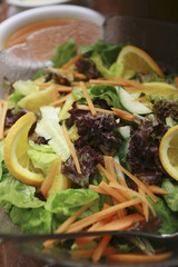A bowl of salad with sliced lemon and carrots