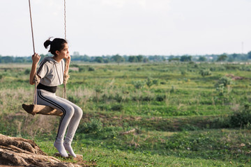 Beautiful girl in outdoor sitting on a swing