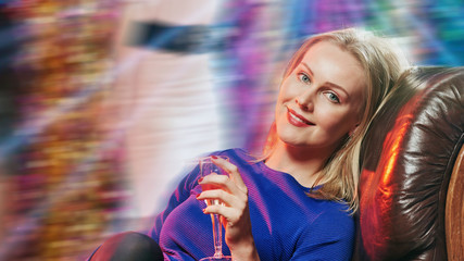 Fototapeta na wymiar Happy relaxed woman with glass of sparkling wine resting in night club