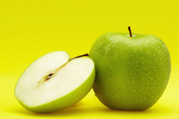 One and a half green apples with water droplets