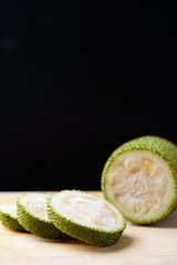 Sliced young jackfruit preparing for cooking on wooden board and black background, Asian food	