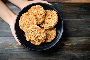Deep fried sweet crispy rice with cane sugar drizzle on plate holding by hand, Local Thai snack (Khao Tan)