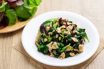Stir fried Thai spinach with egg on white dish and spoon on wooden background, Healthy Thai food