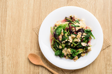 Stir fried Thai spinach with egg on white dish and spoon on wooden background, Healthy Thai food, Top view