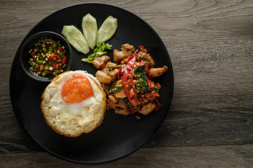 thai food background of spicy thai style stir-fried chicken meat with chilli, basil leaf and garlic served with fried egg topping on rice with chilli fish sauce and cucumber, Thai phat kaphrao rice