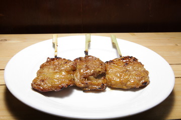 Pork roasted in a white plate placed on a wooden table.