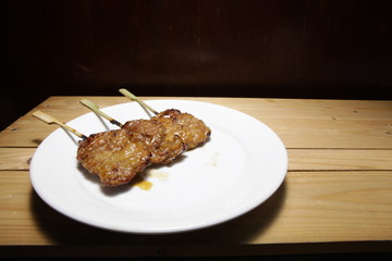 Pork roasted in a white plate placed on a wooden table.