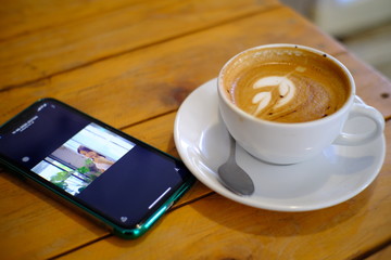 drinks coffee in a cafe(khanom espresso,Thailand) during a meeting. Nearby, a cell phone lies on a table.