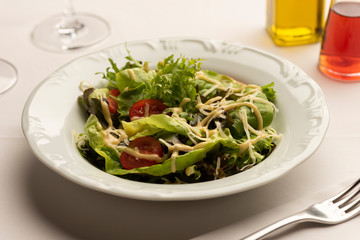 Green salad with lettuce tomatoes on white blurred background