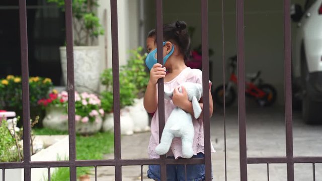 Girl standing behind closed gate during quarantine periode.