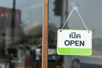 A business sign that says open on cafe or restaurant hang on door at entrance.