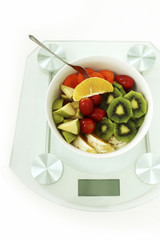 A bowl of fruit and vegetable salad on weight scale