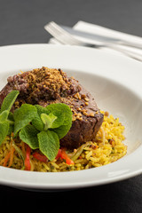 Plate with steak tenderloin and rice with spices ans saffron.