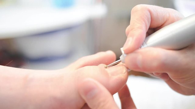 woman master pedicures a man. Hardware pedicure. Leg close up. A man sits in a pedicure chair