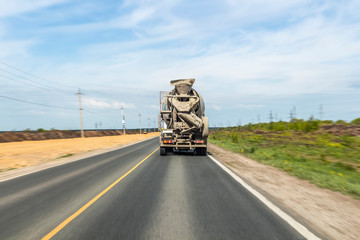 Concrete mixer rides on the road, carrying concrete to the construction site.