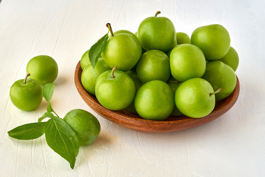 Green sour plum in wooden bowl