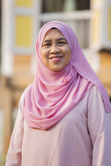 Senior woman standing in front of wooden house