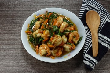 Traditional fried spicy peeled shrimp with chilly and sliced basil on the plate. Famous hot and spicy seafood menu in Asia. Luxury stirred prawn with herbal vegetable. 