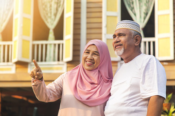 Senior couple standing in front of wooden house