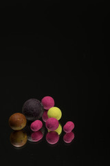 bright green, red boilies, fishing baits for carp isolated on dark background.