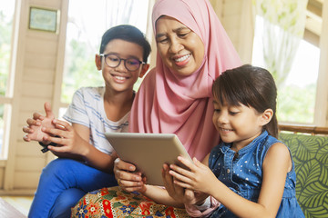 Grandmother and grandchildren using digital tablet