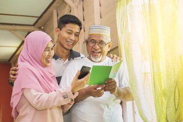 Family with an Eid greeting card and smartphone