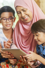 Grandmother and grandchildren using digital tablet