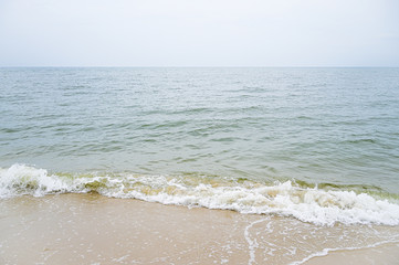 Soft wave with blue ocean on sandy beach.
