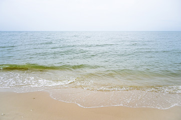 Soft wave with blue ocean on sandy beach.