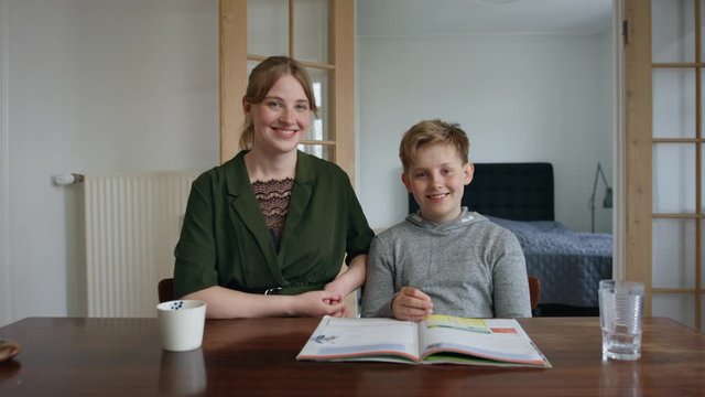 Beautiful Shot of Little Brother and Older Sister and Son Smiling with an Open Textbook in Front