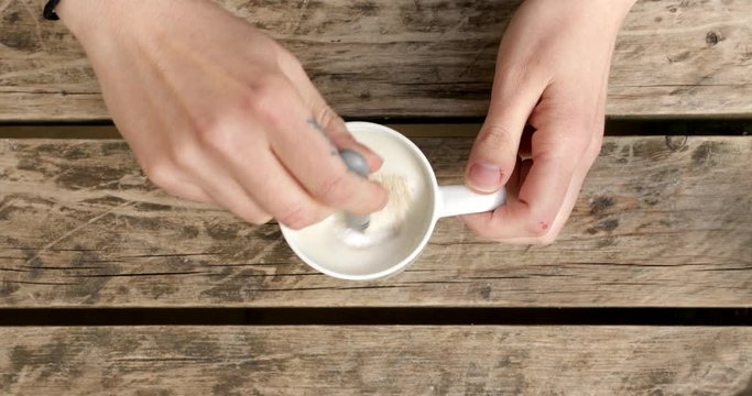 Putting sugar in a mug filled with milk and yeast