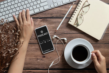 podcast audio content concept. podcast application on mobile smartphone screen on wooden table with...
