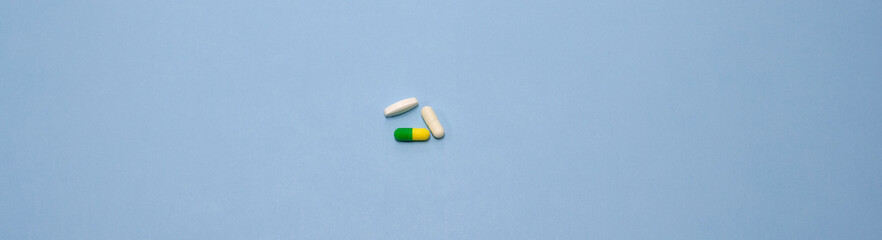 Colorful pills, drugs and capsules in the middle on blue background. Prevention of coronavirus. Web banner on site. Isolated. Medical preparations close up