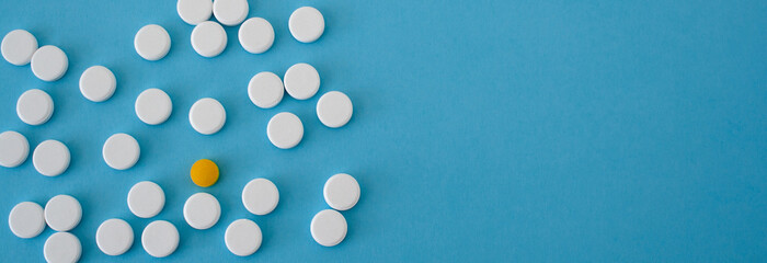 White pills, drugs and capsules on blue background. Prevention of coronavirus. Web banner on site with empty space for text on the right side. Isolated. Medical preparations close up