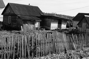 Old dilapidated farmhouse with a fence in Belarus. Abandoned hut in the village. black and white...
