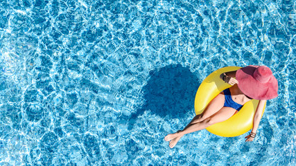 Beautiful woman in hat in swimming pool aerial top view from above, young girl in bikini relaxes...
