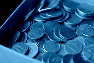 Paper box with a bunch of American cents close up. Money background blue color toned