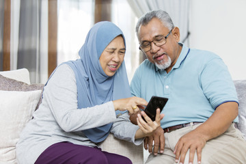 Senior woman showing husband something from the phone